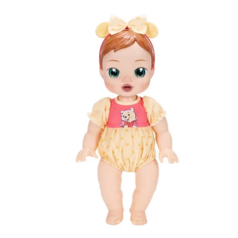 Deluxe baby doll dressed in Pooh-themed outfit with a pink top and yellow bottom, featuring a bow headband.