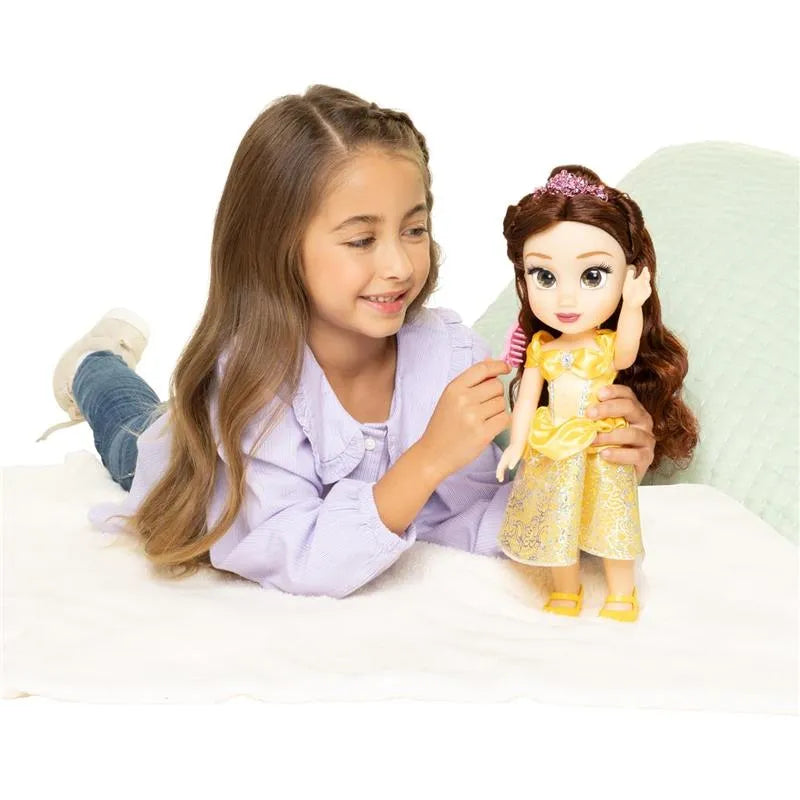 A young girl with long hair is playing with a large Belle doll from Disney, dressed in a yellow gown, while brushing its hair.