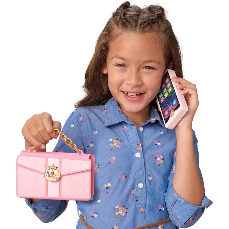 Child holding a pink wristlet phone with a floral shirt, smiling while using the phone on her ear.