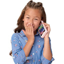 Young girl with braided hair playfully holds a pink toy phone to her ear, smiling with her hand covering her mouth.