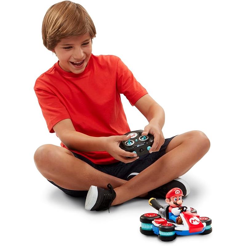 Child in a red shirt using a remote control to operate a Jakks Super Mario Kart 8 mini RC racer with Mario figure.