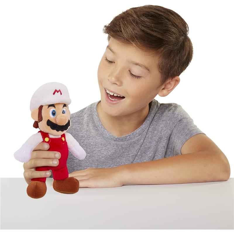 Fire Mario plush toy being held by a smiling boy, showcasing its colorful red overalls and iconic features.