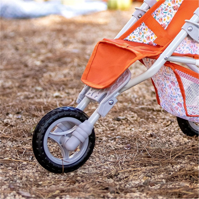Nature jogger with orange fabric, floral accents, and a black wheel, set on a natural surface.
