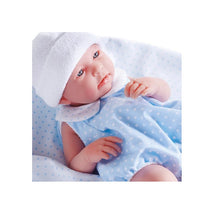 JC Toys La Newborn 17-inch all-vinyl baby doll wearing a blue polka dot outfit and a white hat on a patterned blanket.