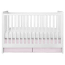 Pleated pink crib skirt draping beneath a white crib with a cushioned white mattress.