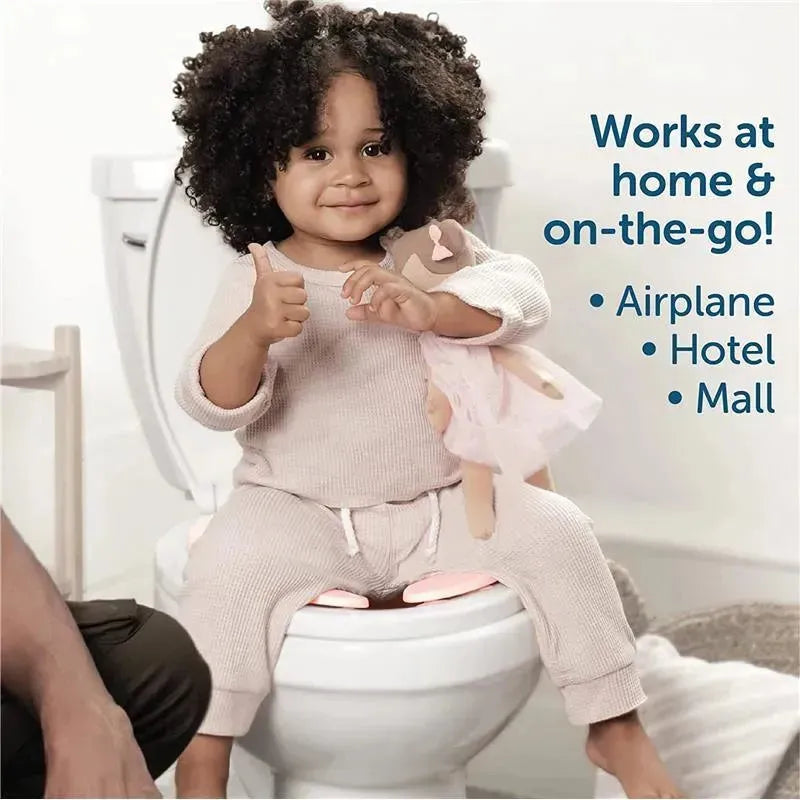 Toddler sitting on a toilet with a folding travel potty seat, giving a thumbs-up while holding a doll.