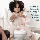 Toddler sitting on a toilet with a folding travel potty seat, giving a thumbs-up while holding a doll.