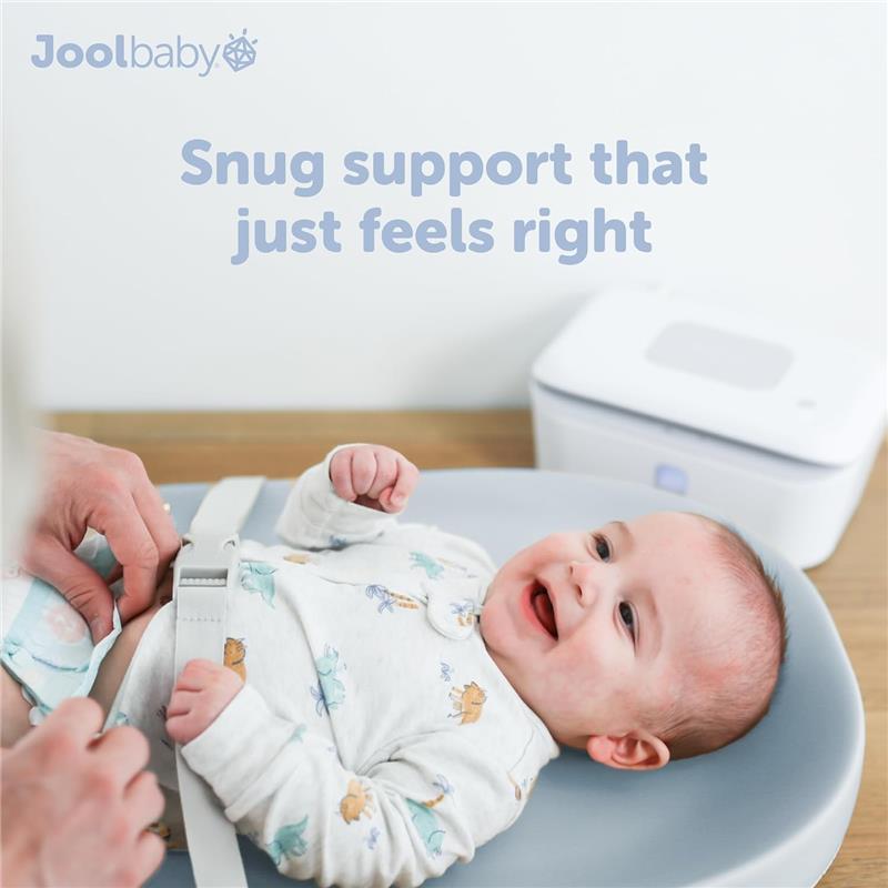 Premium blue changing pad from Jool Baby with a smiling baby secured by a safety strap, and a diaper-changing station in the background.