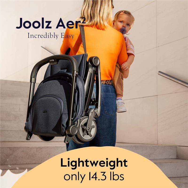 Lightweight Joolz Aer² stroller in sage green, held by a woman carrying a child, showcasing its compact design.