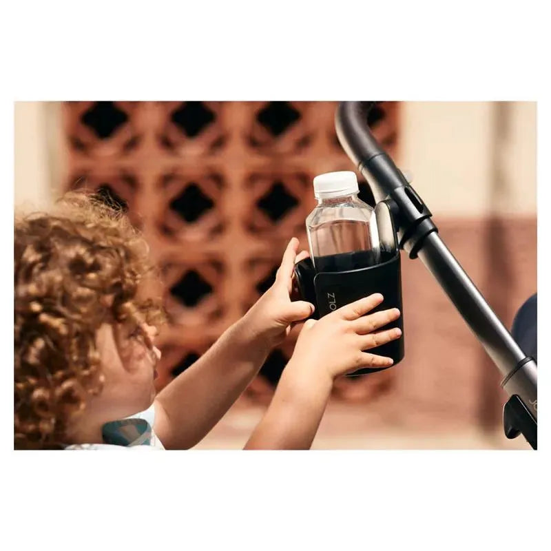 Child placing a water bottle in a Joolz cup holder attached to a stroller.