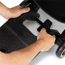 Hands adjusting the Joolz Aer+ Footboard for a stroller, showcasing its black design and attachment mechanism.