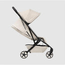 Lightweight compact stroller in calming beige with a black frame and star-shaped wheels, designed for easy transportation.