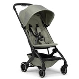Lightweight compact stroller in sage green with a canopy, adjustable harness, and black wheels, designed for easy transport.