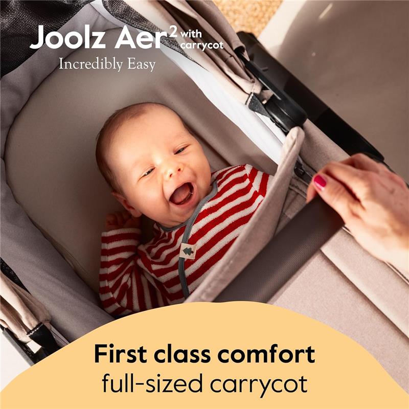 Joolz Aer2 foldable bassinet in Hazel Brown with a smiling baby wearing a striped outfit, showcasing comfort features.