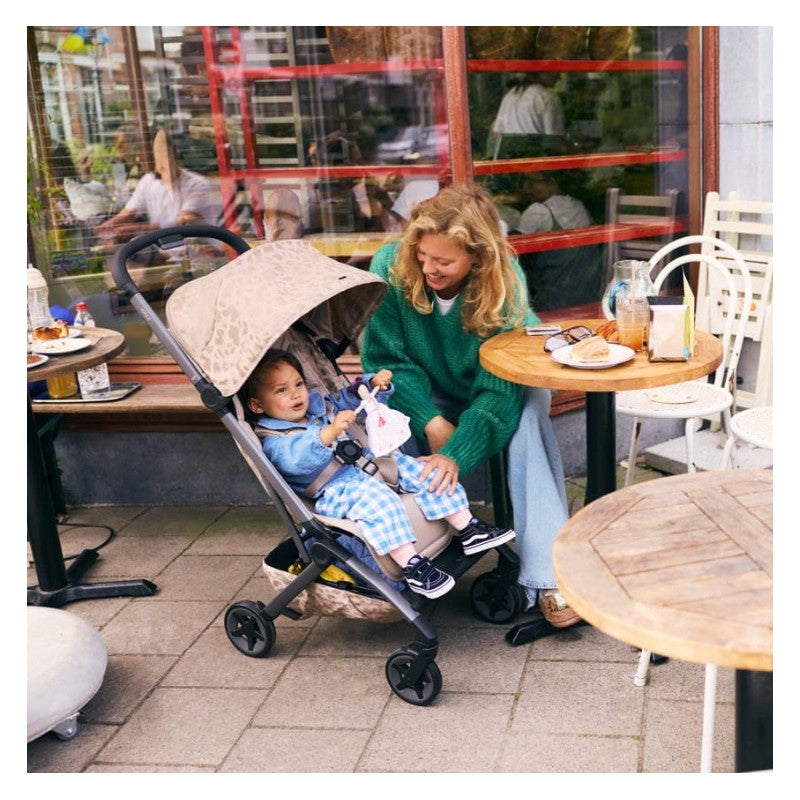 Joolz Aer2 stroller in chic taupe with a child seated, a woman in a green sweater interacts with the child outdoors.