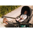 Joolz Hub2 stroller with a seated baby, held by an adult pushing the stroller.