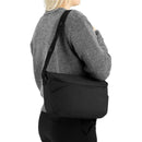 Joolz Organiser Space in black, worn crossbody by a woman in a gray sweater, showcasing its sleek design.