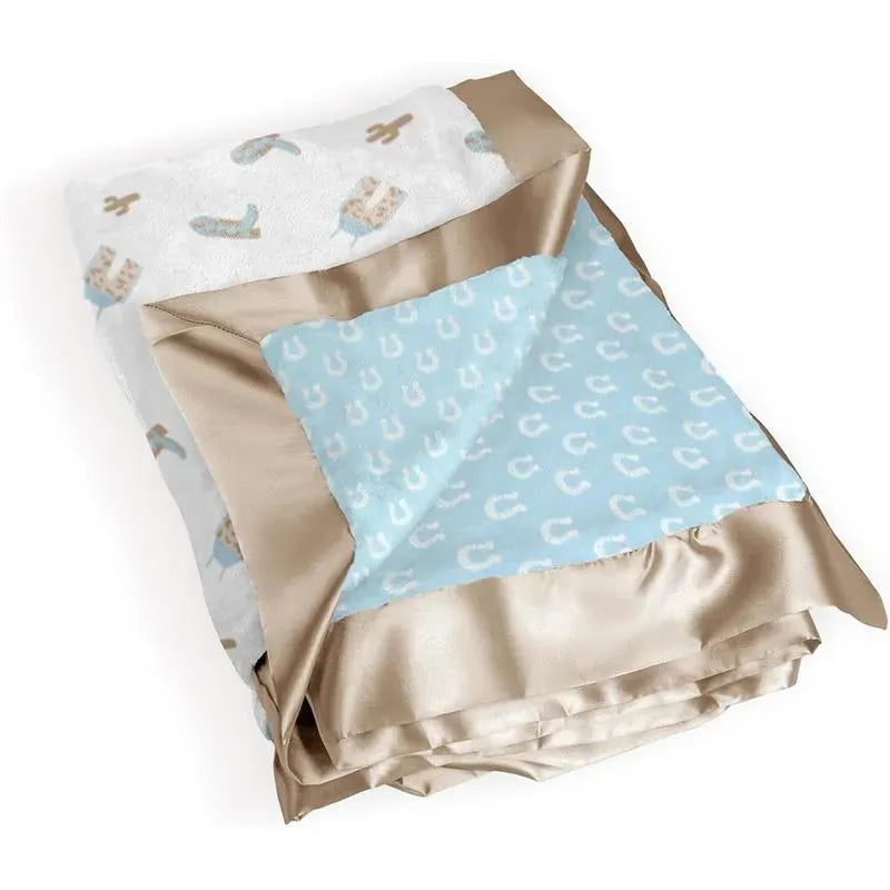 Reversible baby blanket featuring a blue side with horseshoe patterns and a white side with cacti and cowboy boots designs.