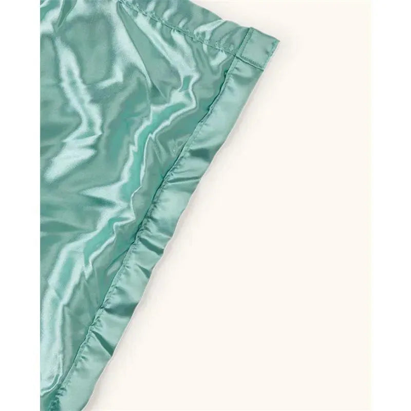 Jujube Sweet Daisy security blanket corner in light teal satin fabric with a gathered edge.