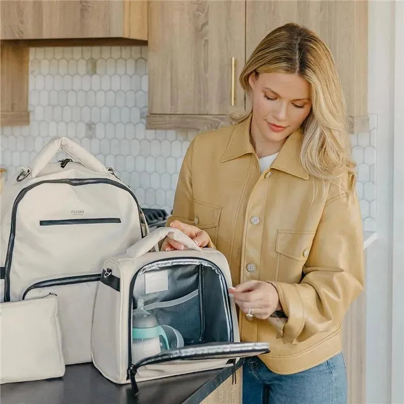 Insulated bottle bag in cloud color, being used by a woman in a beige jacket, with a bottle inside.