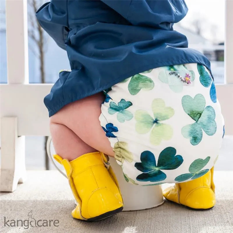 One size cloth diaper cover by Kanga Care in Clover design, featuring green and blue hearts, worn by a child in yellow boots.