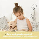 A young girl reads a book while holding a teddy bear, with playful wall art featuring a bunny and balloons.