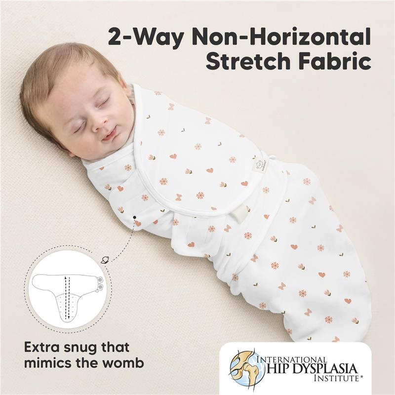Newborn baby swaddled in a white fabric with floral and heart patterns, featuring labels highlighting features for comfort and safety.