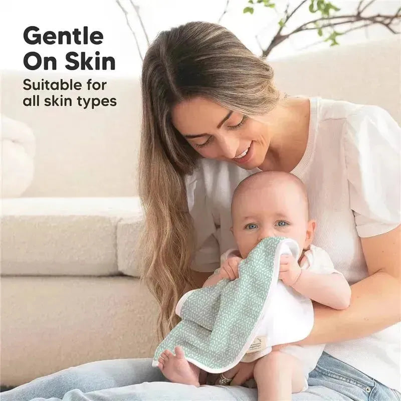 A mother gently holds a baby who is chewing on a soft, mint-colored burp cloth, suitable for all skin types.