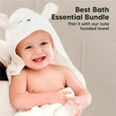 Smiling baby wearing a white hooded towel, holding a washcloth, promoting bath essentials with text overlay.