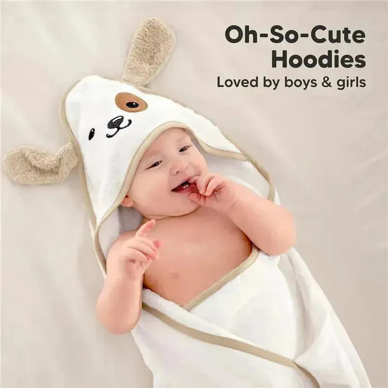 A baby smiling and playing while wrapped in a white hooded towel with dog ears, featuring playful facial design.
