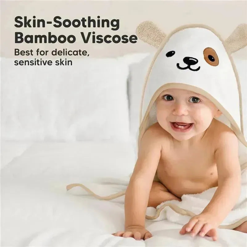 Baby wearing a hooded towel with a dog design, showcasing a happy expression and sitting on a white surface.