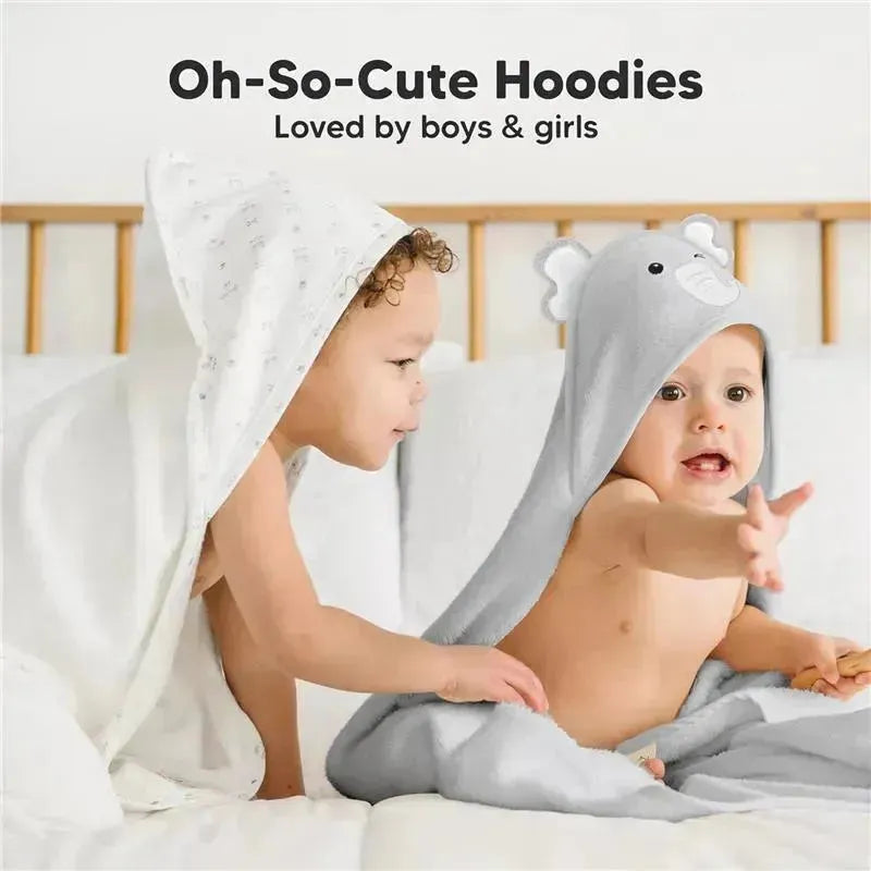 Two toddlers play on a bed, one wearing an elephant-hooded towel and the other in a white hooded towel, showcasing the Keababies brand.