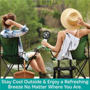 Two people sitting in camping chairs by a river, one holding a black and rose gold Kidco turbofan, promoting outdoor comfort.
