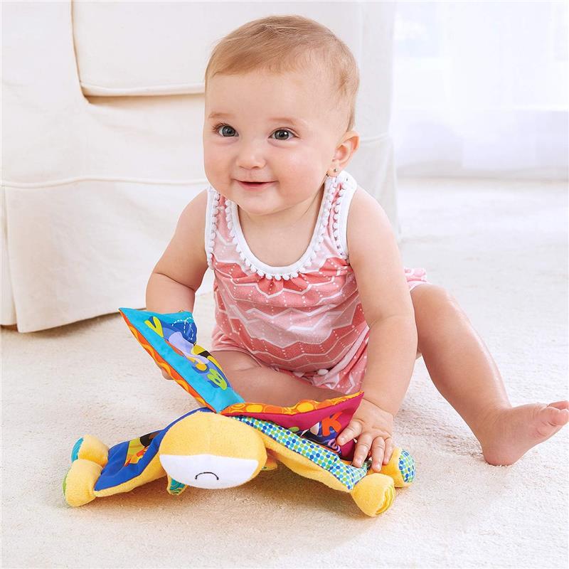 Smiling baby sitting on a carpet, engaging with a colorful, fabric crinkle book featuring farm animals.