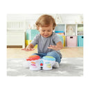 Toddler joyfully plays with Kidoozie Flash Beat Drums, touching colorful drum pads on a soft rug in a brightly colored room.