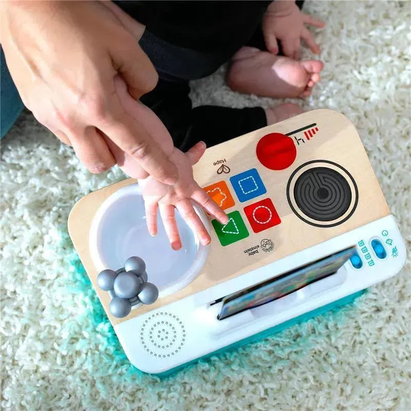 Kids II - Be + Hape Magic Touch Kitchen toy with buttons, a cooking plate, and a hand pressing down, suitable for pretend play.