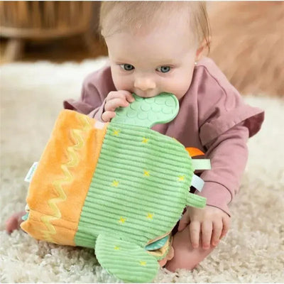 Baby chewing on a soft, colorful teething activity book featuring a cactus design with different textures.
