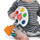 Sensory toy featuring a colorful palette with buttons and lights, held by a child sitting on a floor.