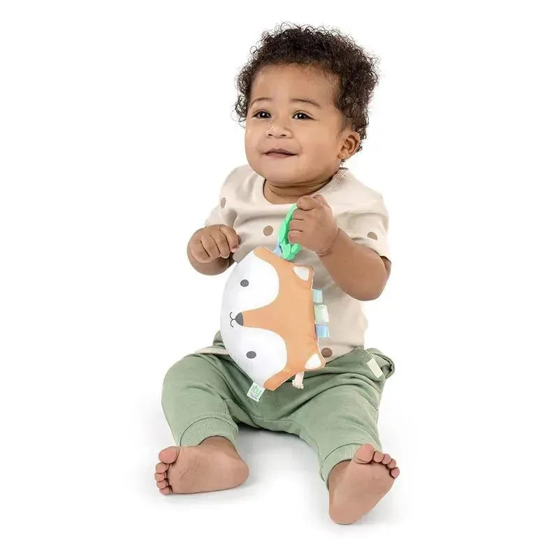 Smiling baby sitting and holding the Kids II Fox Crinkle Toy, Kitt the Fox, featuring a soft, colorful design.