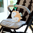 Kitt the Fox crinkle toy hangs from a stroller, featuring a soft fox design with a green attachment ring.