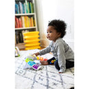 Toddler sits on a patterned rug, interacting with the Kids II Glow & Discover Light Bar Activity Station, colorful and educational.