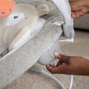 Ingenuity InLighten Baby Bouncer Seat, Natem, with a hand adjusting the control and a plush bear toy visible.