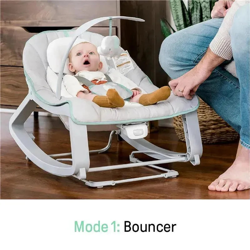 Vibrating baby bouncer with a surprised baby, featuring an overhead toy and a hand adjusting the bouncer mode.