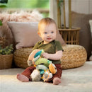 A young child sitting on a soft floor, happily holding the Kids II Nally & Friends Spiral Activity Toy Bar, featuring colorful plush toys.
