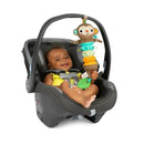 A smiling baby in a car seat holds the Kids II Pull, Play ’N Boogie Monkey Musical Activity Toy.