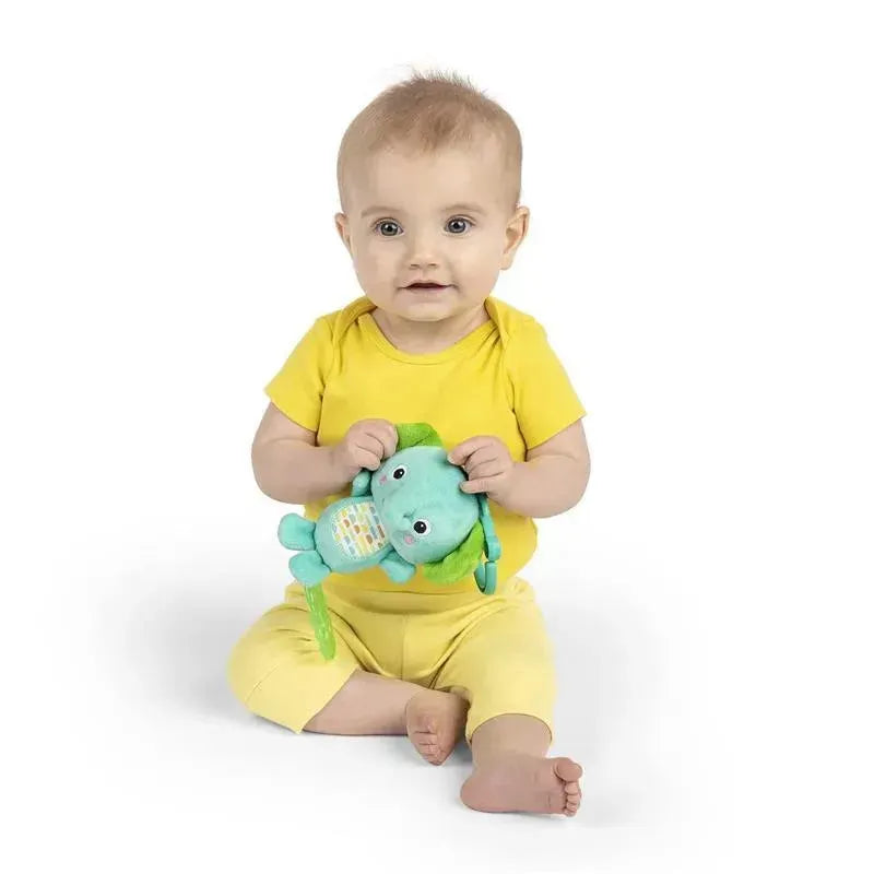 Baby sitting and smiling, holding a colorful Tug Tunes elephant toy, wearing a yellow outfit.