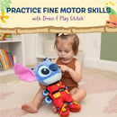 A toddler plays with a Disney Stitch plush toy dressed in a red outfit, focusing on its features to enhance fine motor skills.
