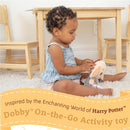 Baby playing with a soft Dobby activity toy from Harry Potter, sitting on a rug near wooden furniture.