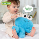 Baby joyfully plays with a blue Sesame Street Elmo plush toy, featuring large eyes and a smile, on a soft surface.