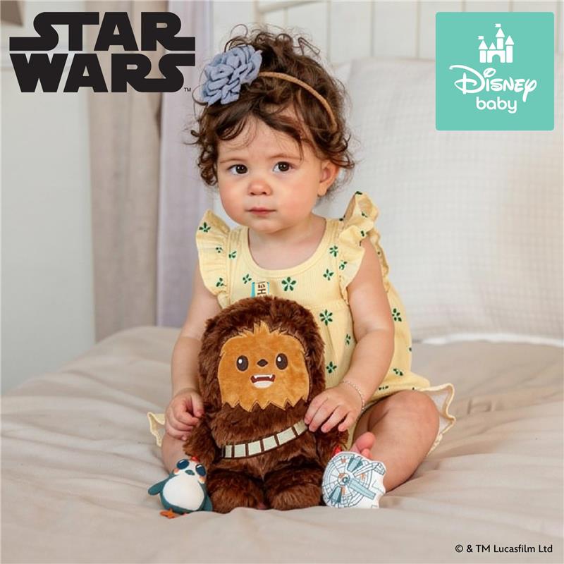 Child sitting on a bed, holding a plush Chewbacca toy wearing a bandolier, with a penguin toy nearby.